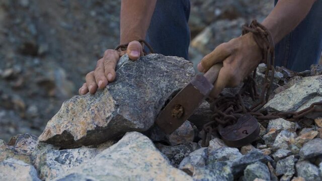 Slave hard work. Hard labor. The convict's hands are holding a hammer. Desire to be free. Desire to break the shackles