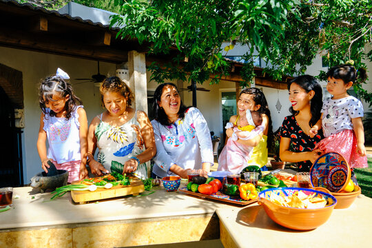 Cheerful multi-generational females preparing lunch at kitchen counter in backyard on sunny day