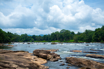 River Flows Between Rocks In Rain forest under blue cloudy sky Chalakudy Kerala