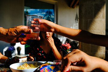 Woman giving girl drink at table with family enjoying lunch during sunny day