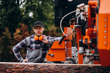 Carpenter working on a sawmill on a wood manufacture - obrazy, fototapety, plakaty