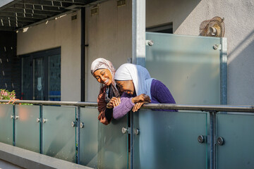 Two young women wearing hijabs leaning on balcony