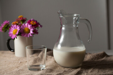 A jug of milk and a glass in a rustic style on a burlap tablecloth