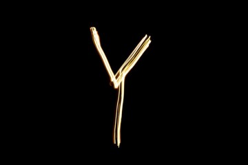 Drawn letter Y with gold lights against black background. Light painting alphabet.