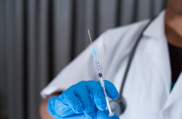 Unrecognizable doctor holding covid-19 vaccine syringe. Closeup shot of male doctor's hand wearing protective surgical glove, syringe ready to for vaccination. 