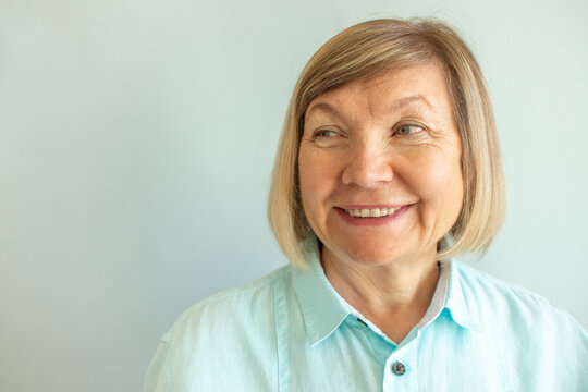 Happy senior woman with gray hair relaxing smiling on a gray background