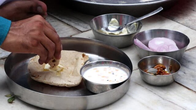 A man eating roti (chapati) with ghee (butter) and raita in the village