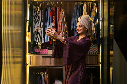 Young newlywed woman clicking a selfie in her mobile in front of her closet.