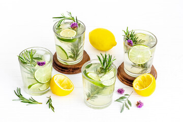 A lot of glasses of lemonade with summer herbs and lemon slices