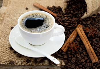 Coffee cup, coffee beans star anises and Cinnamon on wooden table.