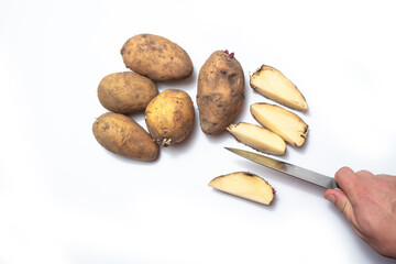 there are potatoes on a white table.next to a cut rotten potato.