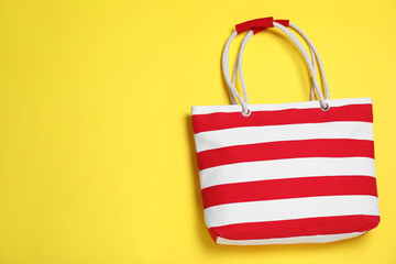 Stylish striped beach bag on yellow background, top view. Space for text