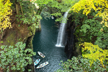 葉に縁どられたボートと滝