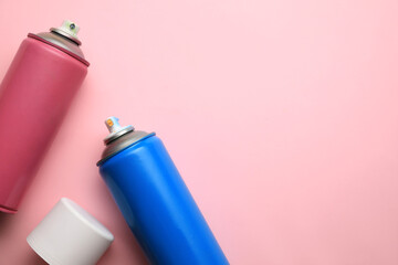 Cans of different graffiti spray paints on pink background, flat lay. Space for text