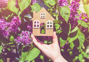 The girl holds in her hand the symbol of the house against the background of blooming lilac