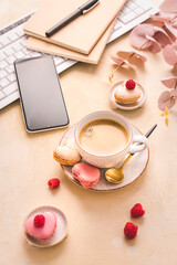 Feminine business workplace with keyboard, writing supplies, cup of coffee and small macarons