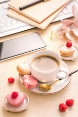 Feminine business workplace with keyboard, writing supplies, cup of coffee and small macarons