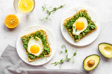 Open sandwich with eggs and avocado on plate. Overhead view
