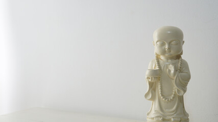 Close view of a white decorative Buddha figure with a bright white wall behind        