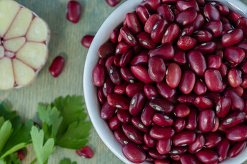 close-up of red beans in a white cup with spices on a wooden table. top view
