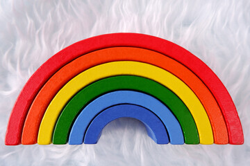 Wooden colorful toy rainbow on a white fur background,similar to an imitation of a cloud.Montessori...