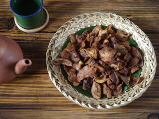 Plateful of keripik pisang or thin banana crisps or banana chips.  Typical Indonesian traditional snack. Sweet and crispy. Rustic wooden table as background.