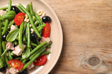 Plate of tasty salad with green beans on wooden table, top view. Space for text