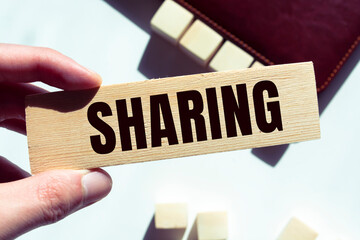 Modern business buzzword - sharing. Word on wooden blocks on a brown background. Close up.