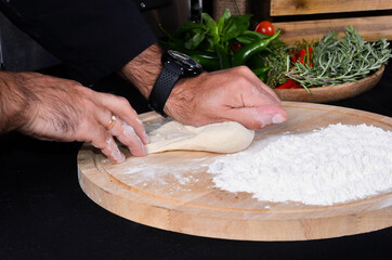 Pizza maker's hands kneading the dough. The cook makes pizza.