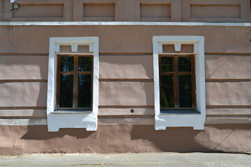 An old windows against the background of a white clay house in the village in summer.
