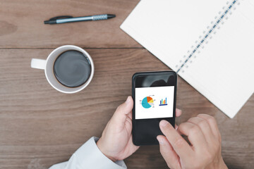 Close hand a man hold smartphone open work for check and pen notebook coffee cup on table