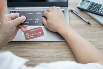 Top view a man hold credit card enter card number on laptop computer on wood table for shopping online order