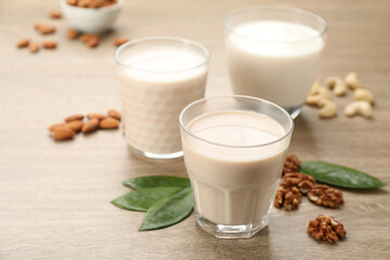 Different vegan milks and nuts on wooden table, closeup