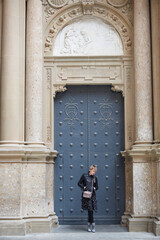 Montserrat, Spain - April 5, 2019: Young wonan poses in front of the Santa Maria de Montserrat Abbey, Catalonia, Spain.