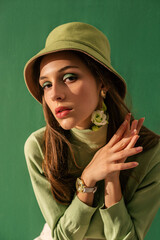 Fashion portrait of elegant woman with green eyes makeup, wearing trendy green bucket hat,...