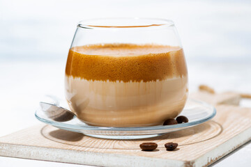 milky coffee with cream foam in glass on white background, closeup