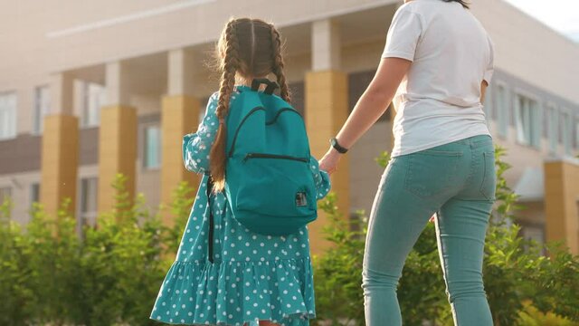 back to school. mom and daughter a go hand in hand to school for lesson. sun education training support concept. child walk to school with a backpack. daughter and mom rush to school. family day