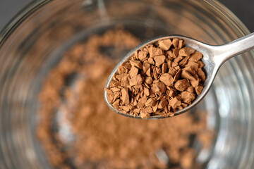 Freeze Dried Instant Coffee on Tea Spoon with Glass Coffee Cup Background.