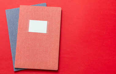 School notebooks stack, old fashioned, on red color background, blank label, copy space, top view.