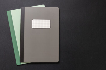 School notebooks stack, old fashioned, on black color background, blank label, copy space, top view.