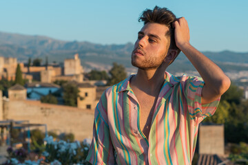 Handsome Caucasian guy wearing a striped shirt posing in the street