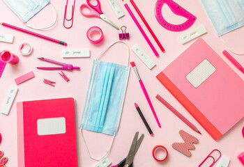 Back to school Covid 19 days. School supplies and Coronavirus measures flat lay. Rapid test, protective medical mask and stationery on pink background