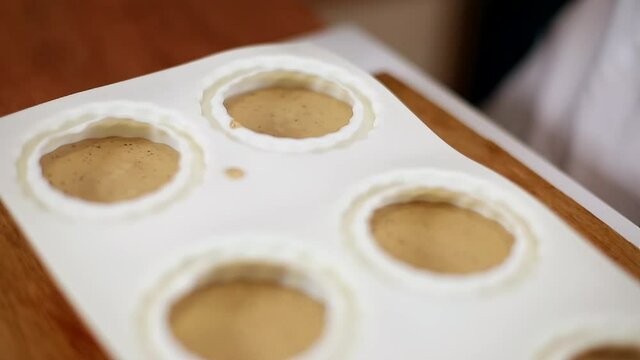 Pocess of professional confectioner making desetr on kitchen. Woman pouring crem into container for freezing