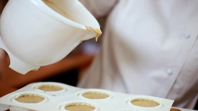 Pocess of professional confectioner making desetr on kitchen. Woman pouring crem into container for freezing