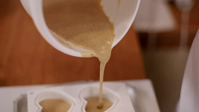 Pocess of professional confectioner making desetr on kitchen. Woman pouring crem into container for freezing