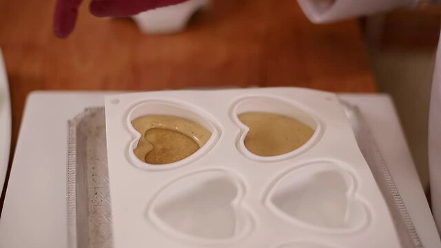 Pocess of professional confectioner making desetr on kitchen. Woman pouring crem into container for freezing