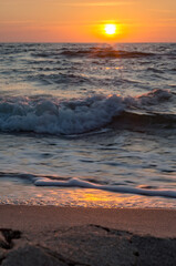 Sunset over the sea. Reflection of sunlight in the sea waves. Red and yellow sky in the rays of the sunset.
