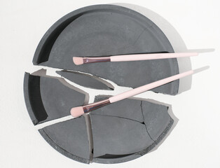 cosmetic eye shadow brushes on broken cement tray. minimal style. professional make up tools. white backround. 
