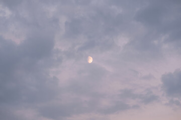 Half moon behind dappled cloud