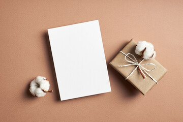 Invitation or greeting card mockup with gift box and natural cotton plant flowers decorations